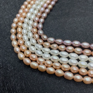 Macro detail of multi-colored rice-shaped freshwater pearls on a black textured background