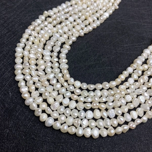 Strands of irregular white freshwater pearls with natural luster on a black background