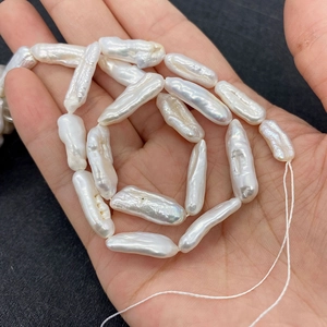 Detalle de perlas Biwa blancas naturales con brillo iridiscente sostenidas en la mano