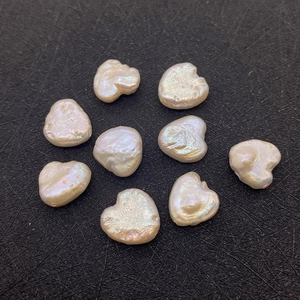 Detail view of 11-12mm natural baroque pearl beads with irregular heart shapes on black background