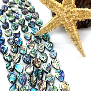 Macro view of teardrop and carved leaf natural abalone shell beads with iris sheen