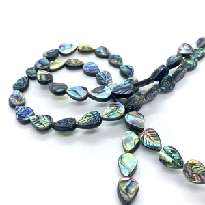 Macro detail of leaf-shaped natural abalone shell beads showing iridescent texture and veins