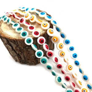 Colorful Evil Eye shell beads for jewelry making displayed on a rustic wood stand