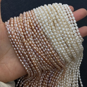 Détail de perles d'eau douce ovales naturelles tenues à la main en blanc et rose-orangé