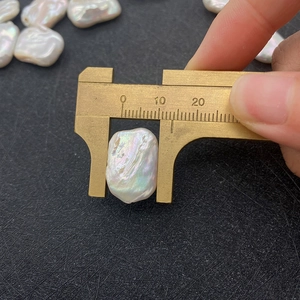 Makroaufnahme einer 12mm Barockperle beim Messen mit Messschieber und irisierendem Glanz