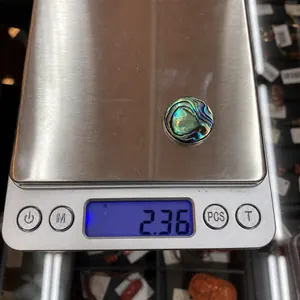 Foto macro de un cabujón de concha de abulón de 2,36g en báscula para medición de peso