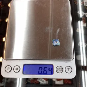 Macro detail of a square abalone shell inlay on a digital scale weighing 0.64 grams