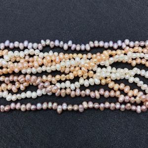 Makroaufnahme von 4-8mm Süßwasserperlen in Weiß, Creme und Lila auf schwarzem Hintergrund