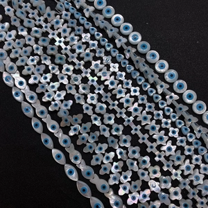 Detailansicht der weißen Muschelperlen in Hamsa- und Sternform mit bösem Blick