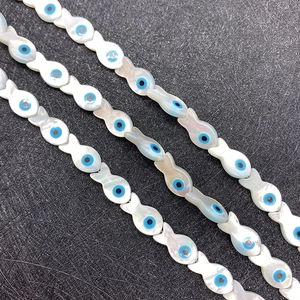 Macro shot of fish-shaped mother of pearl shell beads with blue evil eye inlay design