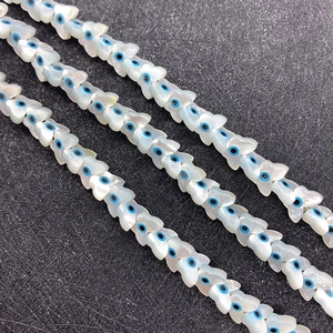 Macro detail of butterfly shaped shell beads with blue evil eye inlay for DIY jewelry