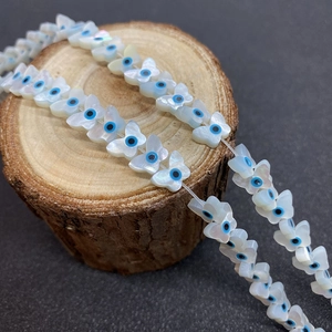 Détail macro de perles en nacre papillon avec motif œil bleu sur un support en bois