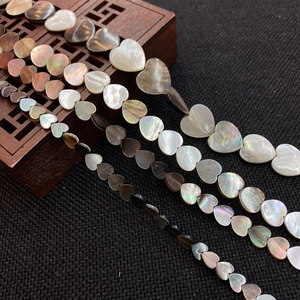Macro detail of heart-shaped natural shell beads with rainbow iridescence on wood