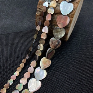 Macro shot of heart-shaped iridescent natural shell beads in various sizes on wood