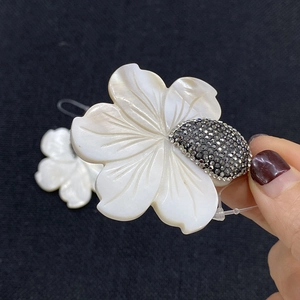 Pendentif fleur en nacre naturelle avec cœur serti de diamants sur fond noir