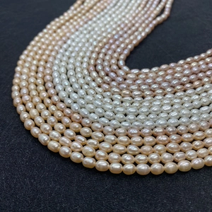 Macro shot of colorful rice-shaped freshwater pearls in white pink and orange on black