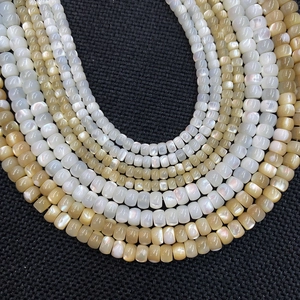 Macro detail of natural freshwater shell beads in white and gold on a dark mesh surface