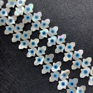 Macro shot of natural white shell Hamsa hand beads with evil eye design for jewelry