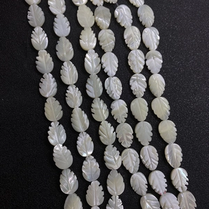 Natural white shell leaf beads with carved veins and iridescent luster on black background