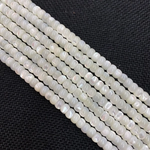 Macro shot of natural white shell beads with pearlescent luster on black textured fabric