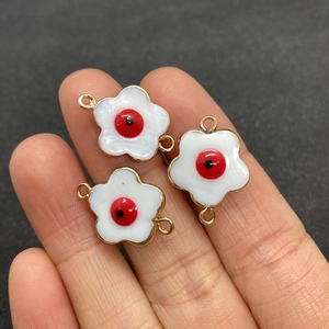 Macro shot of three evil eye shell flower connectors on a finger for size reference
