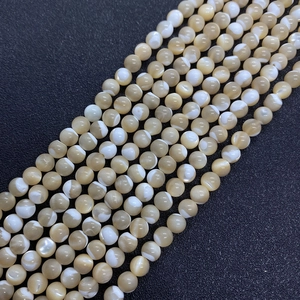 Makroaufnahme von polierten Naturmuschelperlen mit creme-weißer Marmorierung für Schmuck