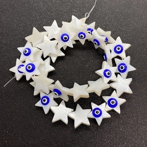 Makroaufnahme von sternförmigen Perlmuttperlen mit blauem Evil Eye für DIY-Schmuck