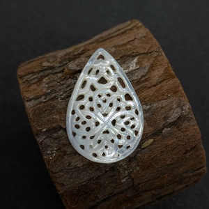 Détail d'un pendentif en nacre en forme de goutte avec sculpture florale ajourée