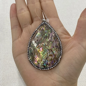 Pendentif goutte en nacre d'abalone avec bordure de cristaux sur fond blanc