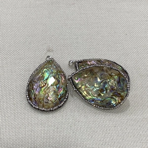 Détail macro du pendentif en nacre d'abalone avec bordure en strass argentés brillants