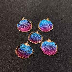 Détail de cinq pendentifs en coquillage dégradé avec des bords dorés galvanisés