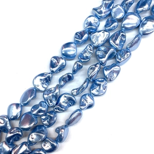 Detailed view of light blue irregular natural shell beads with metallic pearl coating
