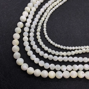 Cremeweiße Perlen aus natürlicher Muschel für DIY-Schmuck auf schwarzem Hintergrund