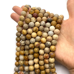 Natural coral jade round beads held in hand showing earth-toned rock textures and 8-10mm size