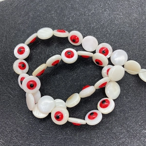 Makroansicht von 10 mm runden Muschelperlen mit rot-schwarzem Böser Blick Design für DIY