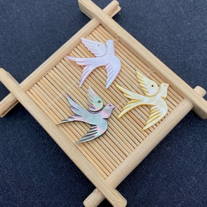 Dettaglio di pendenti a forma di rondine in conchiglia con riflessi iridescenti e fori
