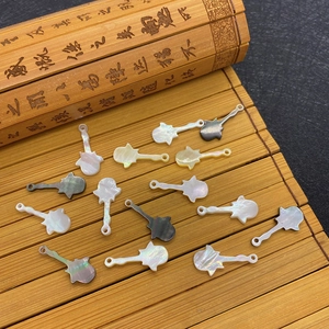 Guitar-shaped natural shell pendants in assorted colors on a rustic bamboo mat background