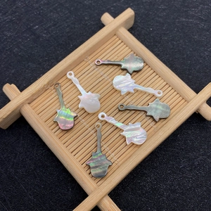 Detailed macro view of guitar-shaped natural shell pendants with iridescent luster and top hole