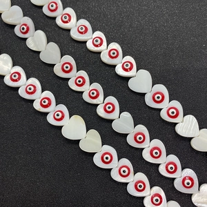 Macro shot of natural shell heart beads with evil eye inlay for DIY necklace making