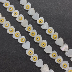 Macro detail of heart-shaped shell beads with evil eye motif for DIY jewelry making