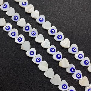 Macro shot of heart-shaped shell beads featuring evil eye detail for jewelry making