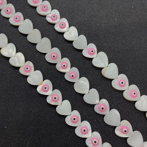 Macro detail of natural shell heart beads with evil eye inlay for jewelry making