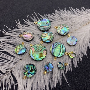 Natural round abalone shell pendants with golden rings on white feathers and black background