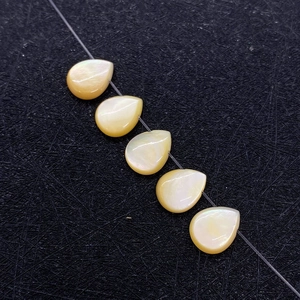 Five yellow teardrop mother of pearl shell beads with iridescent luster on black background
