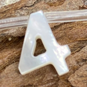 Macro shot of letter A natural seashell bead with iridescent luster for DIY necklace