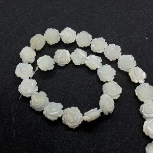 Macro shot of 8mm white carved shell rose beads with iridescent mother of pearl luster