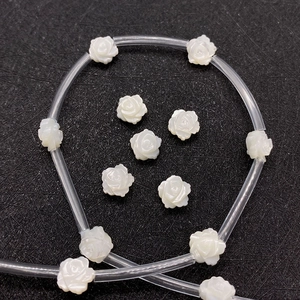 Macro shot of white carved shell rose beads with iridescent luster for DIY jewelry making