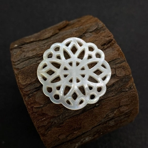 Vue macro d'une perle en nacre sculptée en forme de fleur sur un support en bois