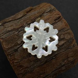 Vue macro d'une perle en nacre en forme de flocon de neige avec des cœurs évidés