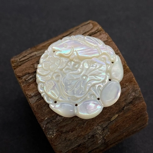 Détail macro d'un pendentif en nacre naturelle sculptée à la main avec lotus et poisson